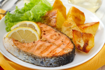 fried salmon with lemon and potato on the plate