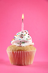 tasty birthday cupcake with candle, on pink background