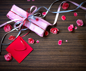 Present,gift bow with petal from flowers on wooden table/