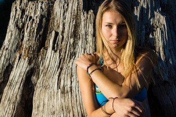 Fototapeta premium Beautiful Woman in Blue Bikini sitting on weather tree stump