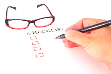 Checklist with pen, glasses and checked boxes.