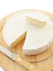 Circle Brie  cheese on wooden desk with knife isolated