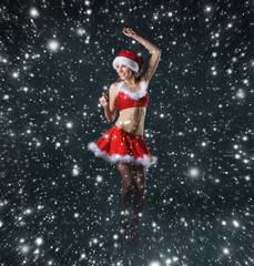 A young and sexy girl in a Santa costume on a snowy backgrond