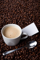 Frischer Kaffee in Bohnenhaufen mit Notiz und Löffel
