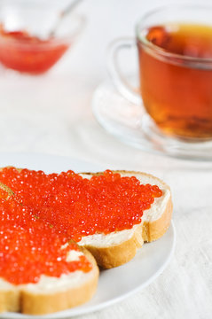 Red caviar on a slice of bread and tea