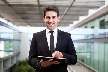 Fototapeta na wymiar Smiling young businessman using his digital tablet at the office
