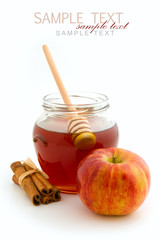 Honey in glass jar and apple with cinnamon sticks