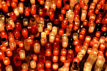 Many burning candles in graveyard at night