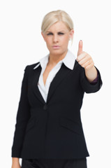 Obraz premium Serious blonde businesswoman thumb-up