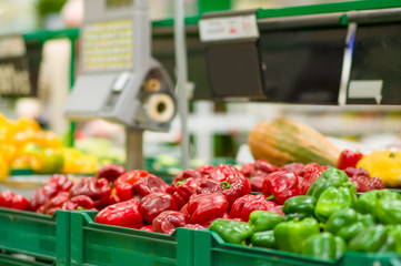 Red and green paprika peppers in boxes in supermarket