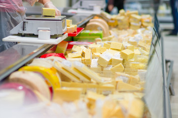 Pieces of different cheeses in fridge in supermarket