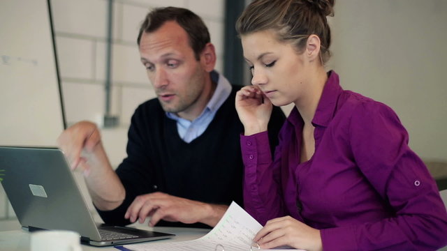 Worried business people in office with laptop and documents 