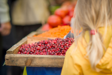 Girl stay near table with wild berries on city market