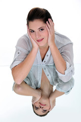Woman smiling and leaning on her reflection in a mirrored table