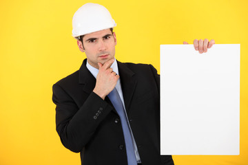 A pensive architect holding a poster.