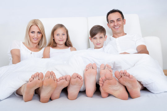 Happy Family In Bed Under Cover Showing Feet