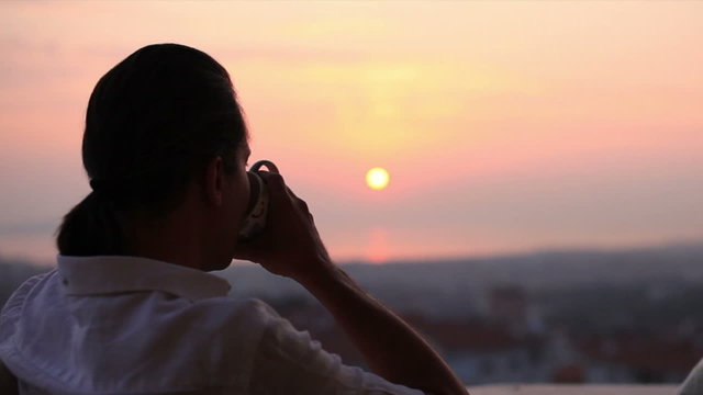 man watching sunset and drinking