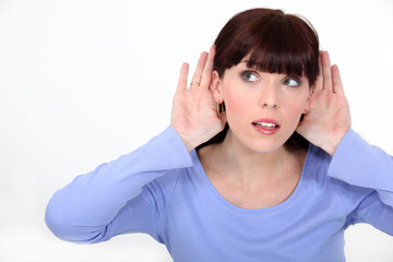 Woman with her hands to her ears listening