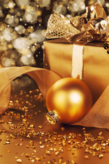 goldene christbaumkugel neben weihnachtsgeschenk