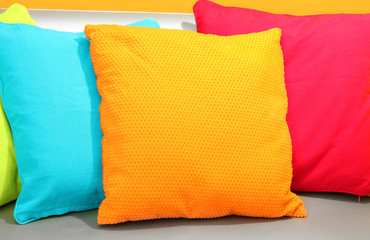 Colorful pillows on couch on yellow background