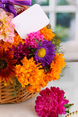 Beautiful bouquet of bright flowers in basket with paper note