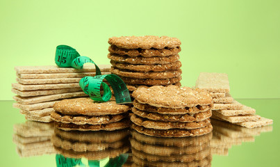 tasty crispbread and measuring tape, on green background