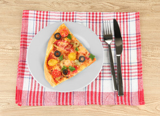 plate with a slice of delicious pizza on wooden background