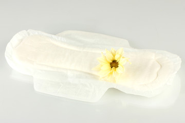 Fototapeta na wymiar Wkładka higieniczna i żółty kwiat na białym
