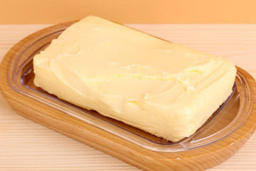 Butter on wooden holder on wooden table on beige background