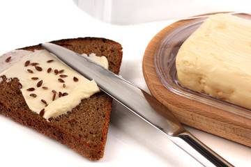 Butter on wooden holder and bread isolated on white