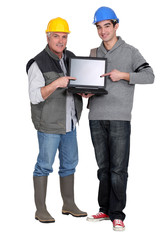 Builder and young helper pointing at laptop