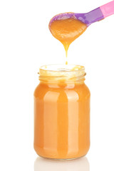 Jar with baby food and spoon on white background close-up