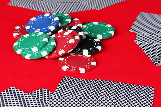 poker chips and playing cards on a red table