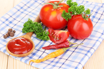 Ketchup and ripe tomatoes on wooden table