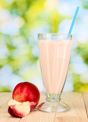 Peach milk shake on wooden table on bright background