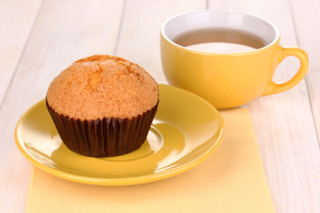 Fresh muffin with tea on wooden background