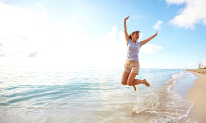 Happy woman jumping on the beach. - Powered by Adobe