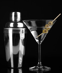 Martini glass with olives and shaker isolated on black