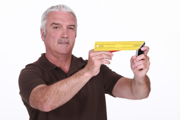 Grey-haired carpenter holding measuring device