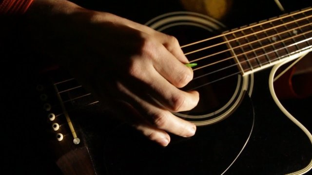 Male hands play on acoustic guitar