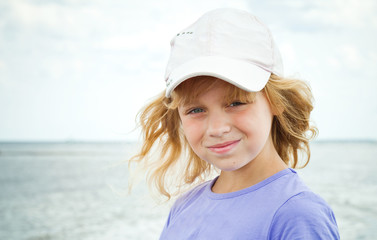 Slightly smiling little girl on the sea coast