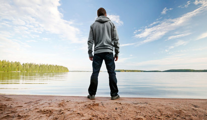 Man stands on the sand coast starring at the horizon