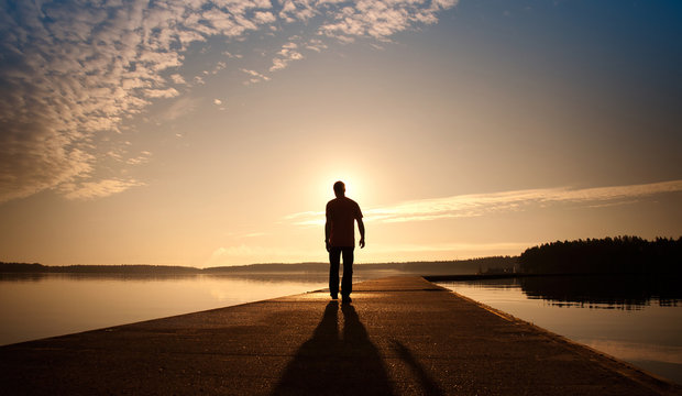 A man goes on the concrete pier in the sunrise