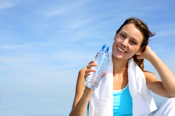 Thirsty fitness girl holding bottle of water