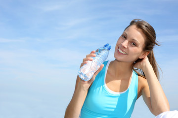 Thirsty fitness girl holding bottle of water