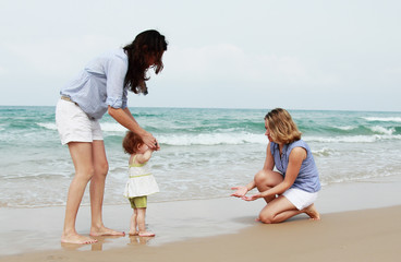 two beautiful girls with a baby on the beach