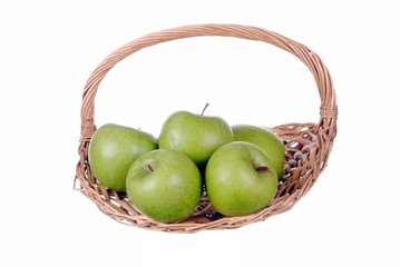 green apples in a straw basket, isolated on white