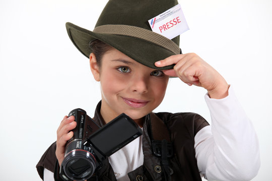 little girl taking a camera and wearing a costume of journalist