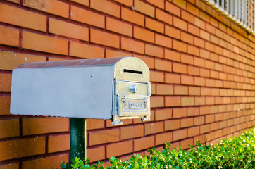 Silver mailbox on a red brick wall in Mexico city