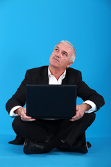 Senior businessman sat on the floor with laptop